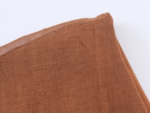 Macro shot of brown linen blend fabric showing detailed weave texture and hem stitching