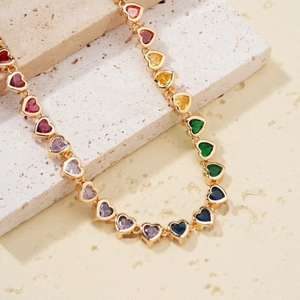 Rainbow heart zircon necklace with gold plated finish on a natural stone display