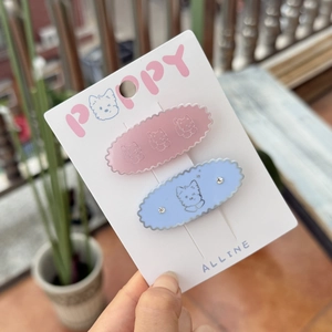 Close-up of pink and blue resin hair clips with cute dog patterns on white card