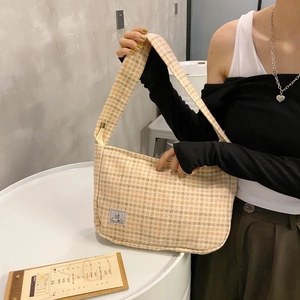 Détail du sac tissé pied-de-poule jaune et beige avec une étiquette de marque SR