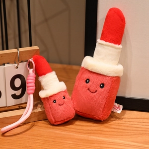 Creative plush lipstick doll set with cute smiling face on a warm wooden background