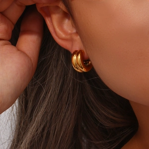 Close-up of stylish double-layered golden C-shaped hoop earrings on a female model