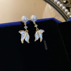 Gros plan sur des boucles d'oreilles pétales blancs dorés avec perles et cristaux