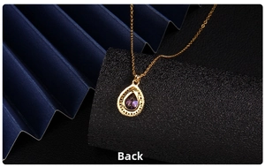 Macro back view of the golden waterdrop pendant showing hollow patterns and purple gemstone