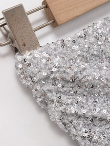Dettaglio di paillettes argento su un top senza spalline con cuciture artigianali