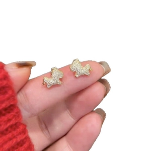 Gold plated dog stud earrings with sparkling white zircons held between fingers