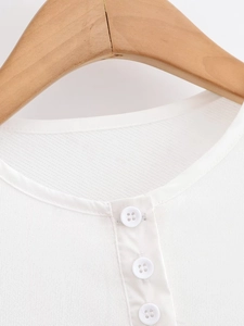 Close-up of white knit fabric with buttoned Henley collar on a wooden hanger