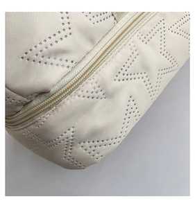 Detailed close-up of perforated star patterns and sturdy zipper on a cream gym bag