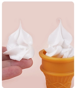Close-up of white swirling clay dollop held by hand and placed on a mini orange cone