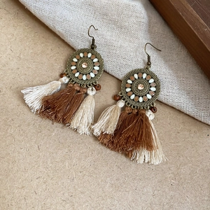 Close-up of bohemian tassel earrings with bronze metal and brown enamel details