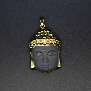 Macro shot of Buddha head pendant with matte black finish and polished gold metal trim