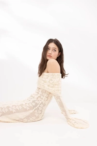 Close-up of off-white hollow knit dress showing intricate crochet textures and soft fabric
