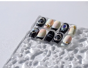 Détail de faux ongles de luxe avec perles 3D, strass et breloques de nœuds en métal