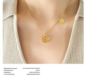 Detalle del collar de titanio bañado en oro 18k con dijes de smiley y Good Luck