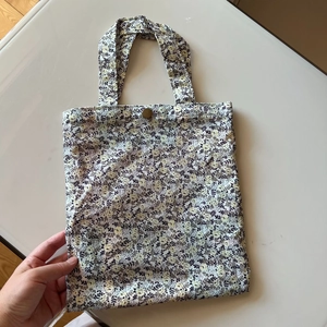 Close-up of small floral cotton handbag with vintage metal button and beige fabric