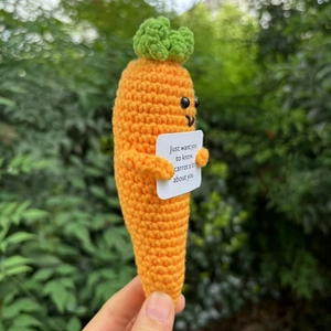 Close-up of handmade crochet carrot doll holding an inspirational carrot pun card