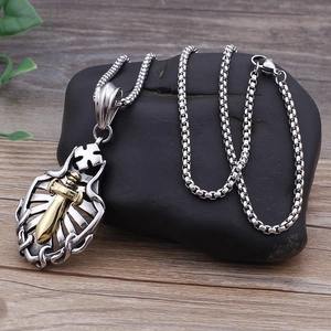 Detail of silver shield pendant with golden sword and cross on black stone