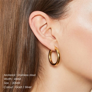 30mm golden stainless steel hoop earring for women worn by a model in a close-up profile view