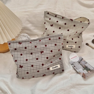 Detail view of polka dot bow pattern and zip closure on the stylish makeup bag