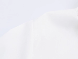 Close-up of the white woven fabric texture and refined stitching of this elegant blouse
