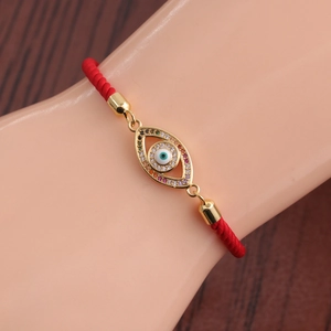 Close-up of red braided rope bracelet with rainbow zircon Evil Eye gold charm