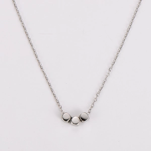 Close-up of three polished silver cubic beads on a delicate stainless steel chain necklace