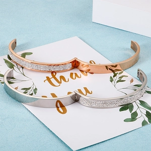 Bracelets en titane or rose et argent avec sertis de cristaux sur fond de sable