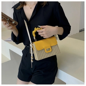 Detail of yellow pleated handle and woven straw body of this stylish crossbody bag