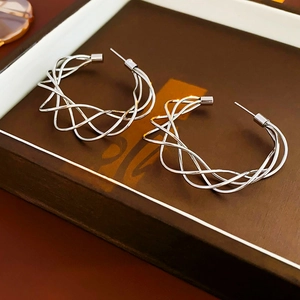 Macro shot of silver-tone hollow twisted C-shape hoop earrings on a dark display tray