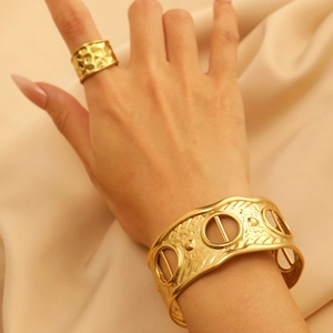 Close-up of gold textured ring and hollow geometric cuff bracelet set on silk