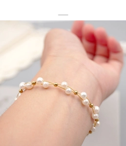 Close-up of elegant freshwater pearl bracelet with gold beads on female wrist