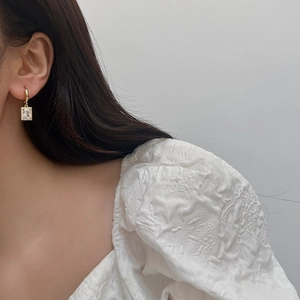Close-up of elegant gold earrings with rectangle zircon crystal and pave-set micro-diamonds