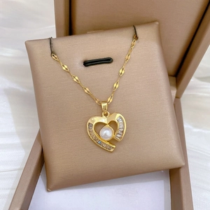 Detailed close-up of a heart pendant necklace with pearls and zircon in a gold jewelry box