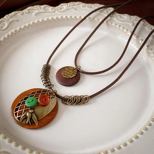 Close-up of ethnic long necklace with wooden pendant, metal bird, and retro button details