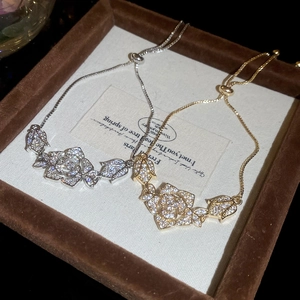 Close-up of adjustable rose flower bracelets with pavé zircons in gold and silver
