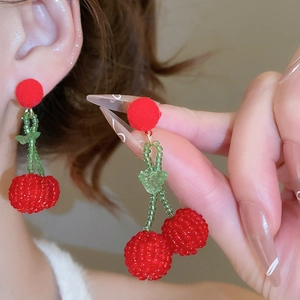 Detail of handmade red beaded cherry earrings with green leaf beads and velvet stud