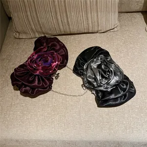 Detailed view of satin rose clutches in purple and black with silver chain straps