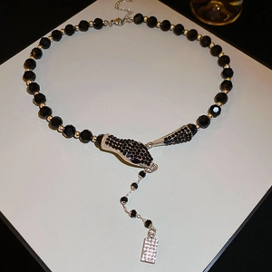Detailed view of snake head pendant with crystal charms and black beaded necklace chain