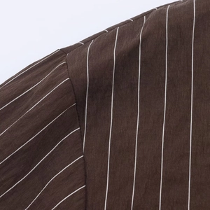 Détail de rayures verticales blanches sur tissu marron et couture de l'épaule