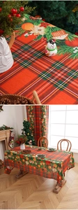 Close-up of red and green plaid tablecloth featuring gingerbread house and pine branch details