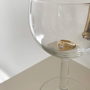 Detailed view of adjustable gold-plated heart ring with zircon set in a glass