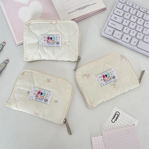 Detailed view of quilted off-white wallets featuring colorful embroidery and zip closure
