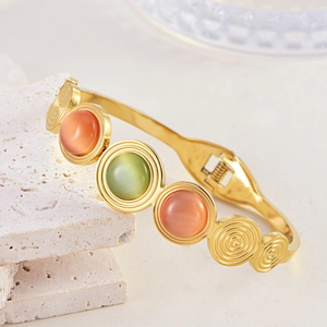 Bohemian gold stainless steel bracelet with green cat eye stone on stone surface