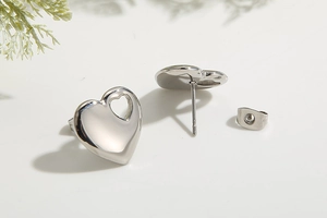 Detailed view of polished silver heart-shaped stud earrings with secure butterfly backs
