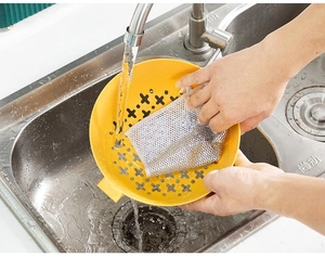 Close-up of silver wire dishcloth cleaning kitchen drainer basket with water flow