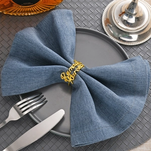 Golden napkin ring with Ramadan Kareem engraving on blue fabric for festive table setting