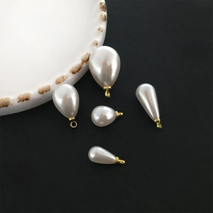 Macro shot of assorted teardrop pearl pendants with gold caps for DIY jewelry making