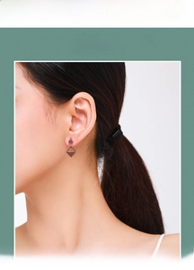 Close-up of geometric S925 silver earrings with red enamel on a female model
