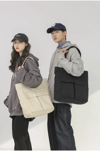 Dual view of large canvas tote bags in cream and black featuring front utility pockets