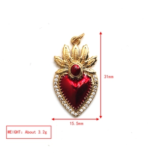 Macro view of gold heart pendant with red enamel, gems and 31mm x 15.5mm dimensions